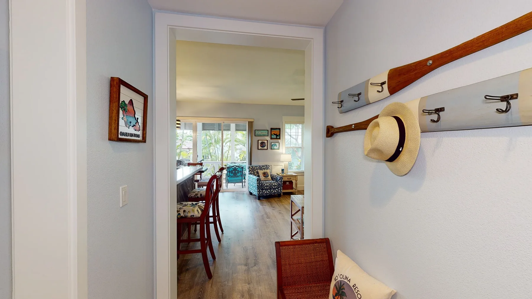 Un salón luminoso se ve a través de una puerta, con asientos y una mesa de comedor.