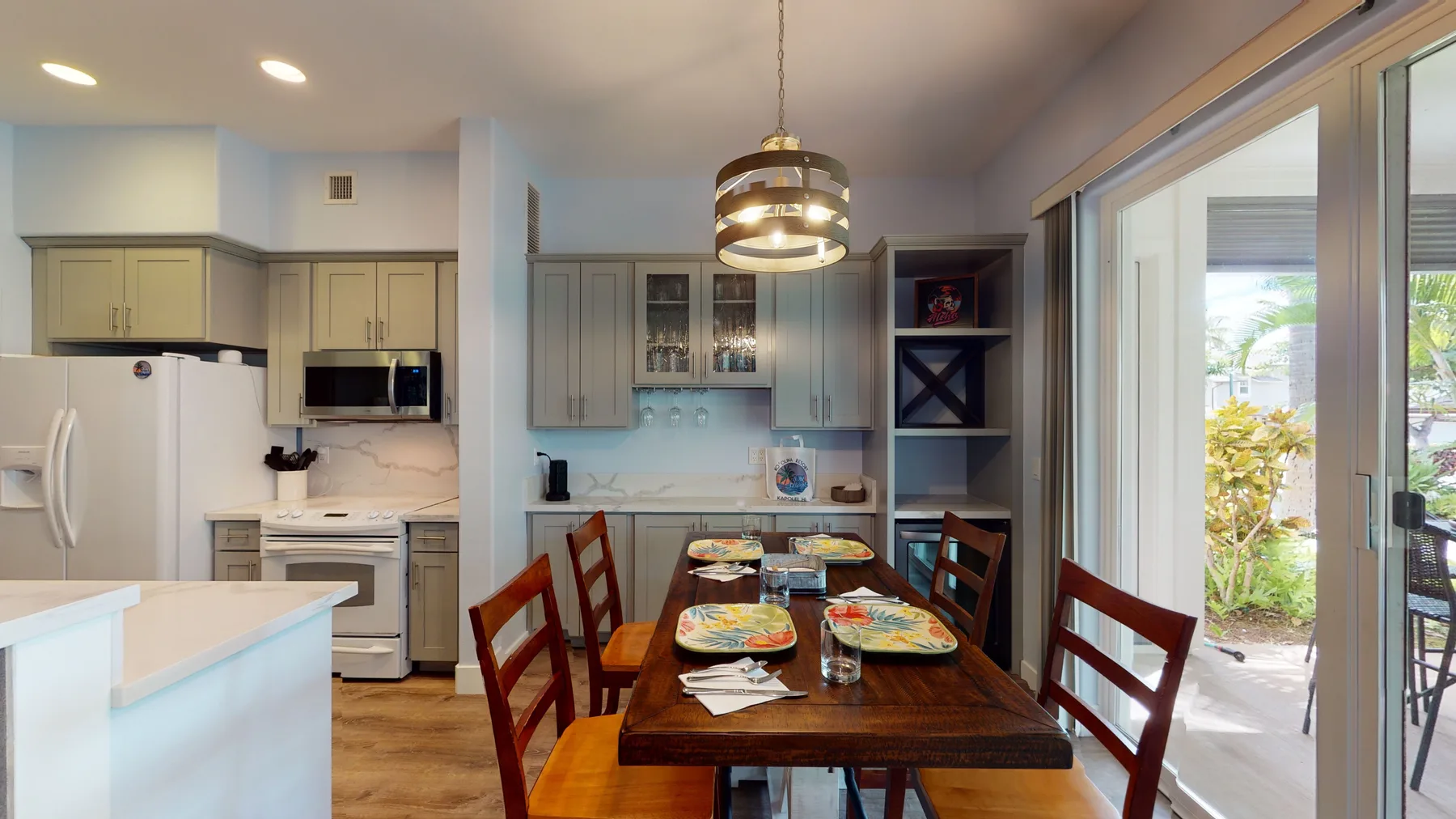 Comedor con una mesa de madera preparada, junto a la cocina y puertas de vidrio.