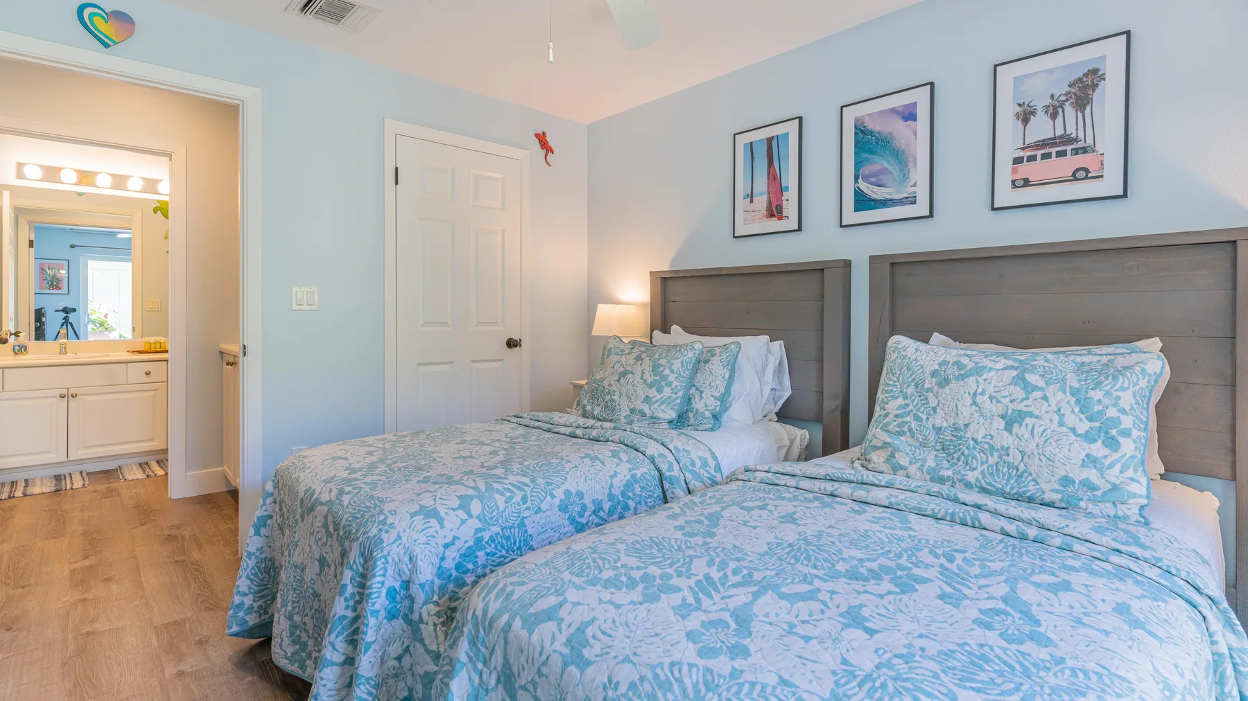 Un dormitorio con dos camas vestidas con ropa de cama azul estampada y cuadros enmarcados.
