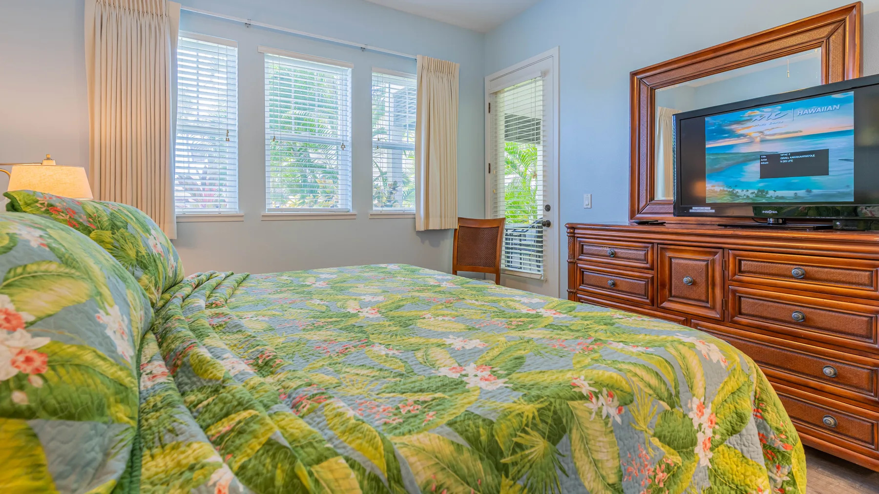 Un dormitorio con una cama cubierta con una colcha floral colorida y un televisor.