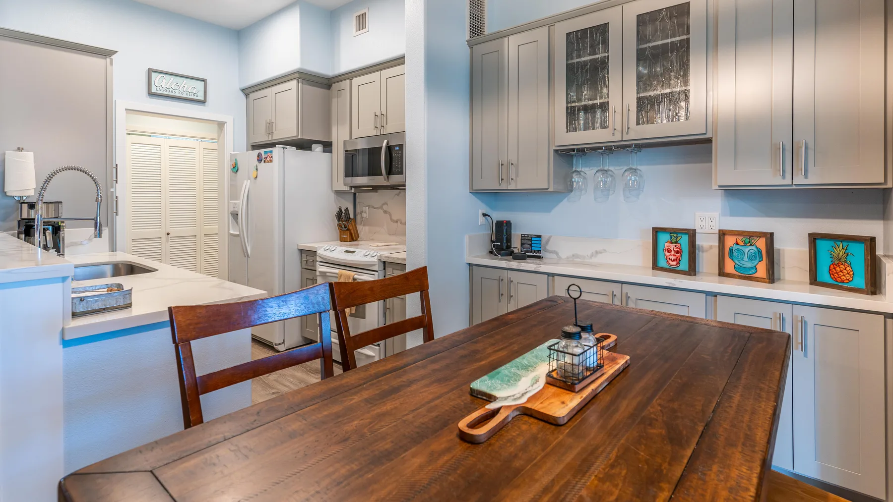 Una cocina y comedor con una mesa de madera y gabinetes claros.