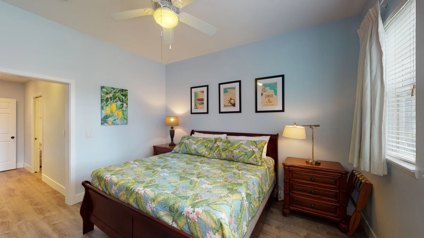 Un dormitorio con una cama vestida con ropa de cama floral y una cómoda de madera.