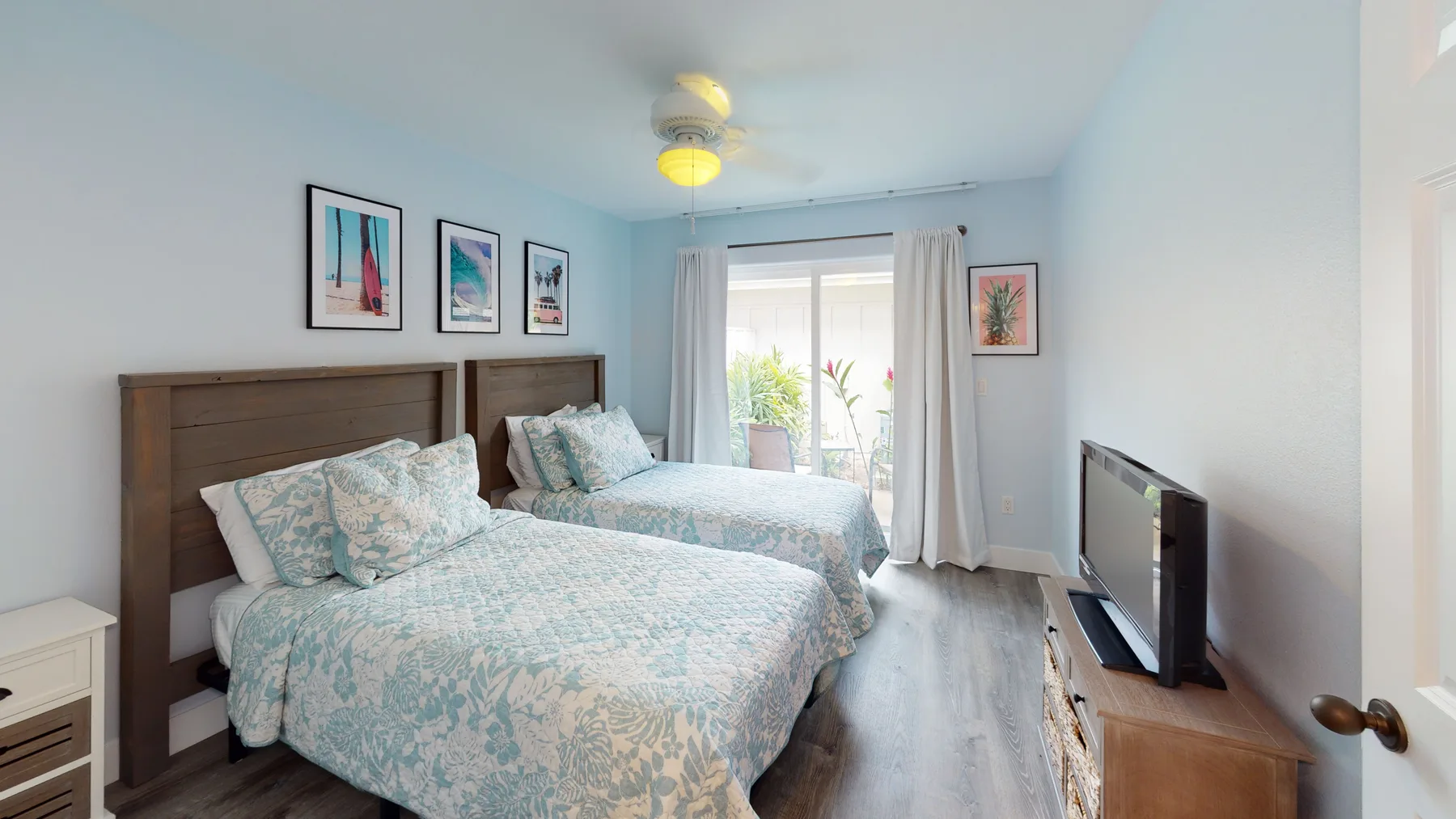 Un dormitorio con dos camas, cuadros enmarcados y un televisor.