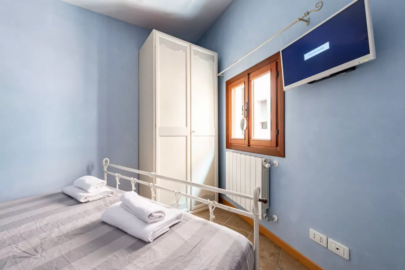 Un dormitorio con una cama, un armario y una ventana.