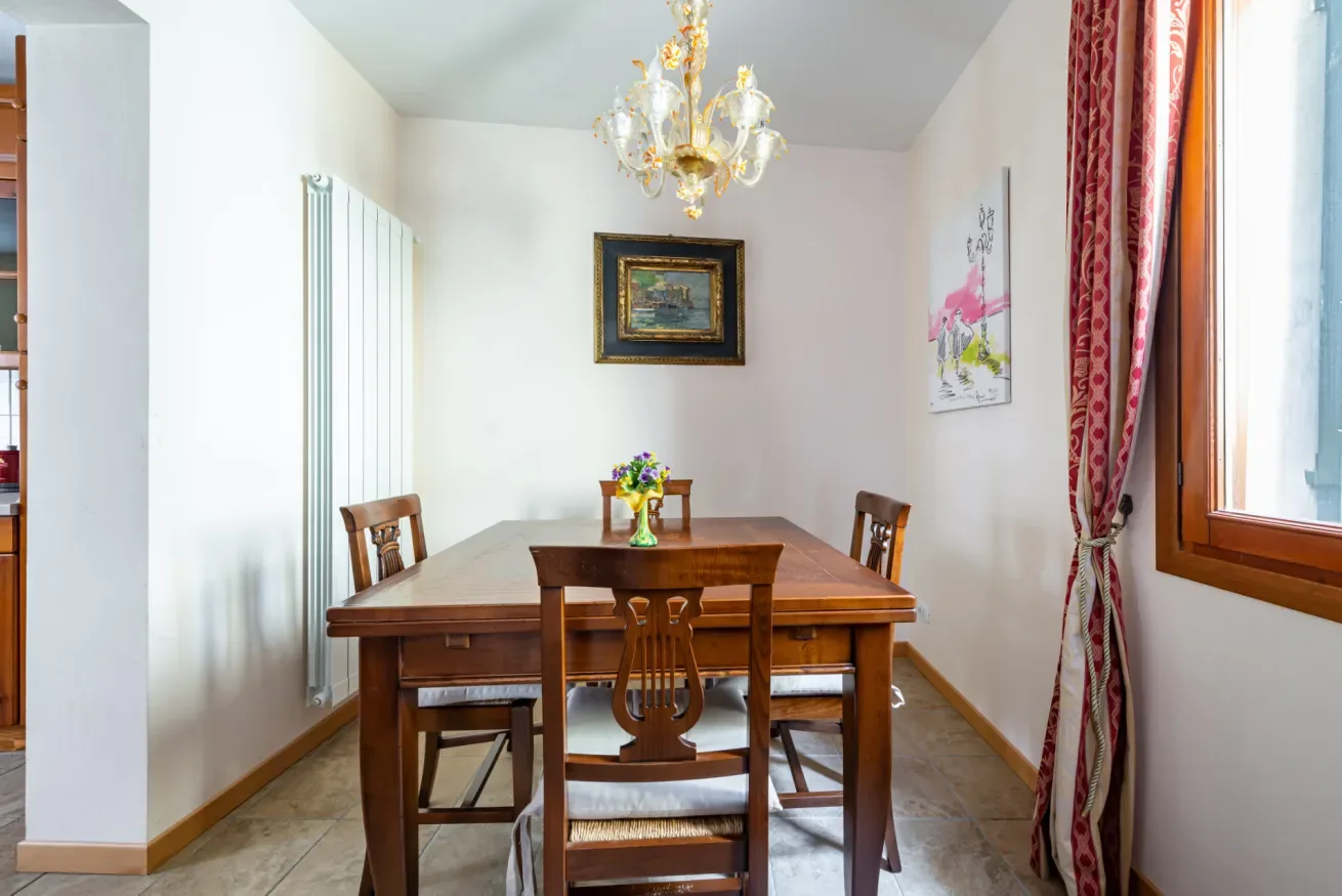 Un comedor con una mesa de madera y sillas bajo una lámpara de araña.