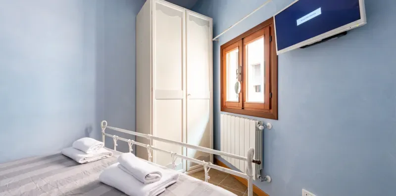 Un dormitorio con camas individuales, un armario y una ventana.