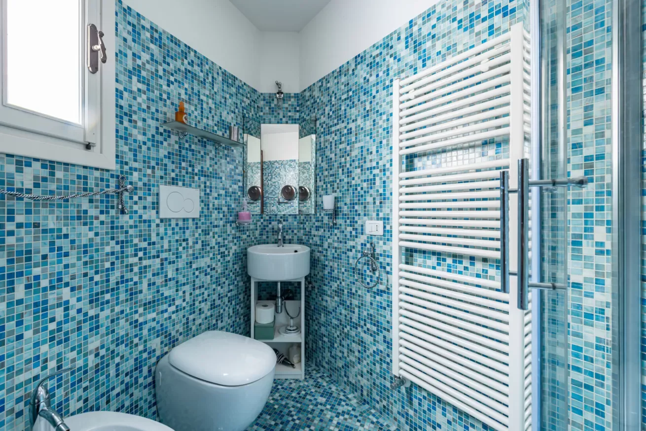 Un baño con mosaicos azules, un inodoro y un lavabo de pared.