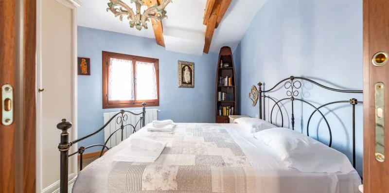 Un dormitorio con una cama, cabecero de hierro y paredes azules.