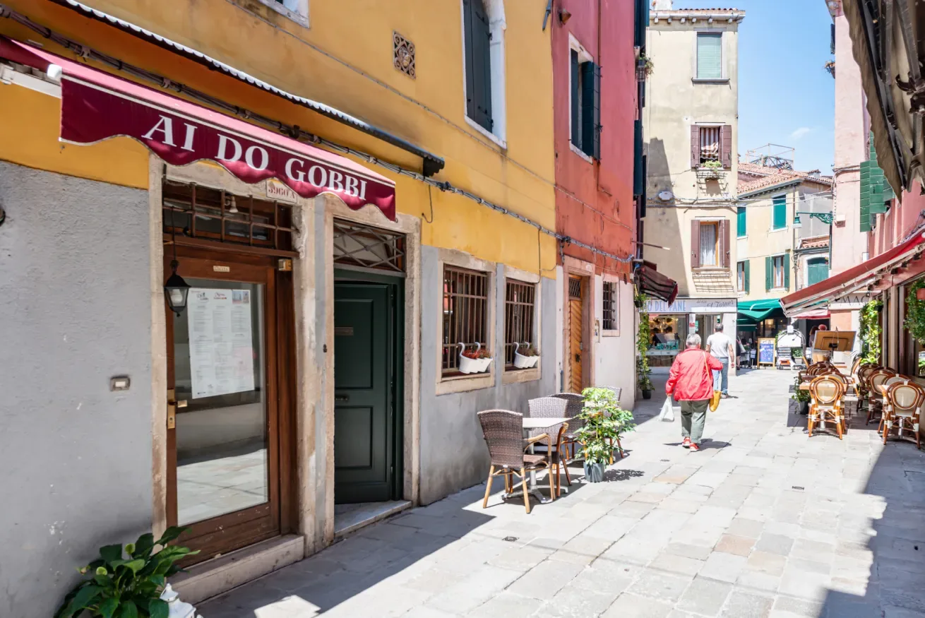 Una calle peatonal con edificios coloridos y mesas de café al aire libre.