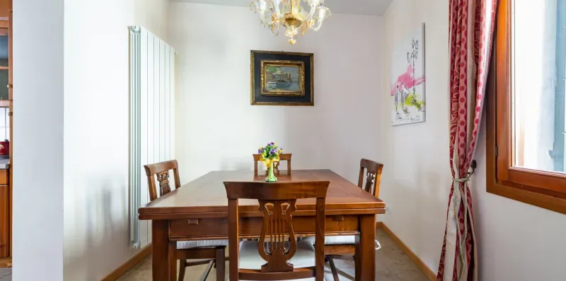 Un comedor con una mesa y sillas de madera bajo una lámpara de araña.