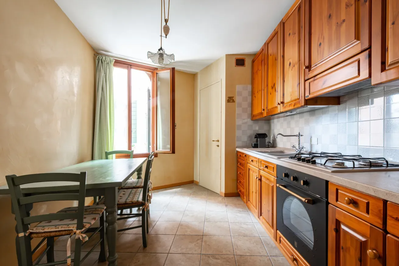 Una cocina con gabinetes de madera, una estufa y una mesa de comedor junto a la ventana.