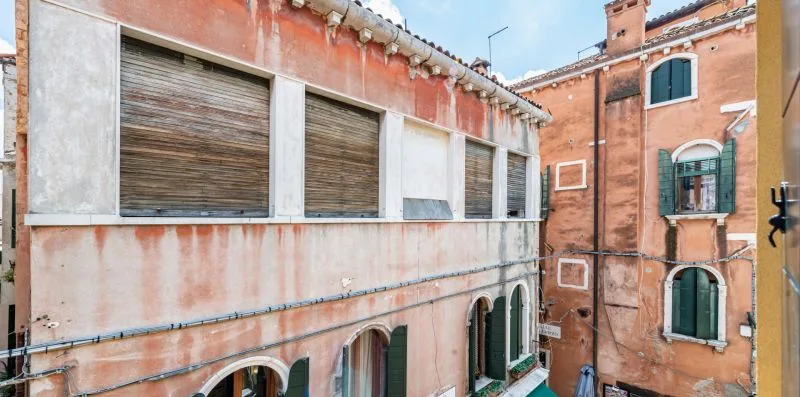 Un patio estrecho está rodeado de edificios de ladrillo con ventanas cerradas.