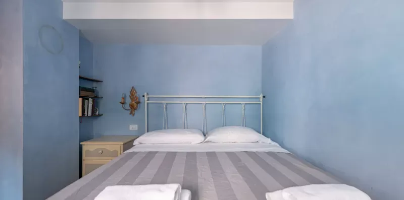 Un dormitorio con una cama, almohadas blancas y paredes azules.