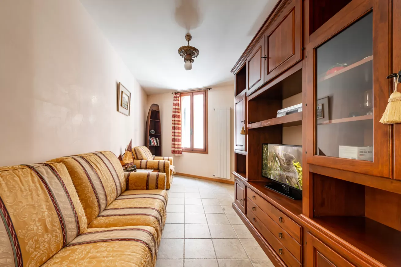 Una sala de estar con asientos estampados y un mueble de entretenimiento de madera.