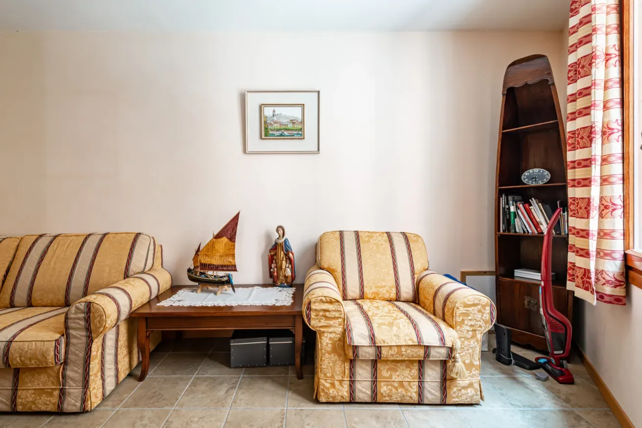 Una sala de estar con asientos estampados, una mesa baja y una estantería alta.