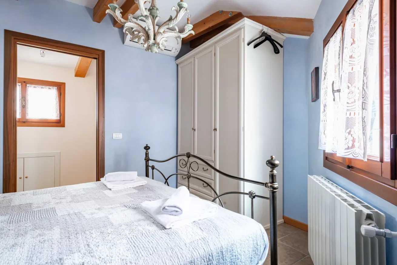 Un dormitorio con una cama bien tendida, un armario y una ventana.
