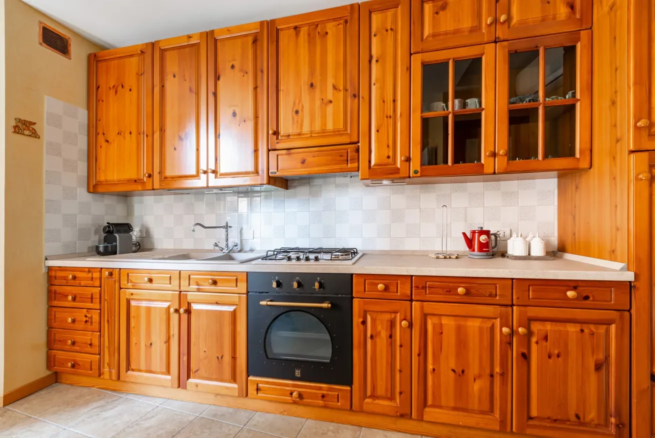 Una cocina con armarios de madera y una estufa sobre la encimera.