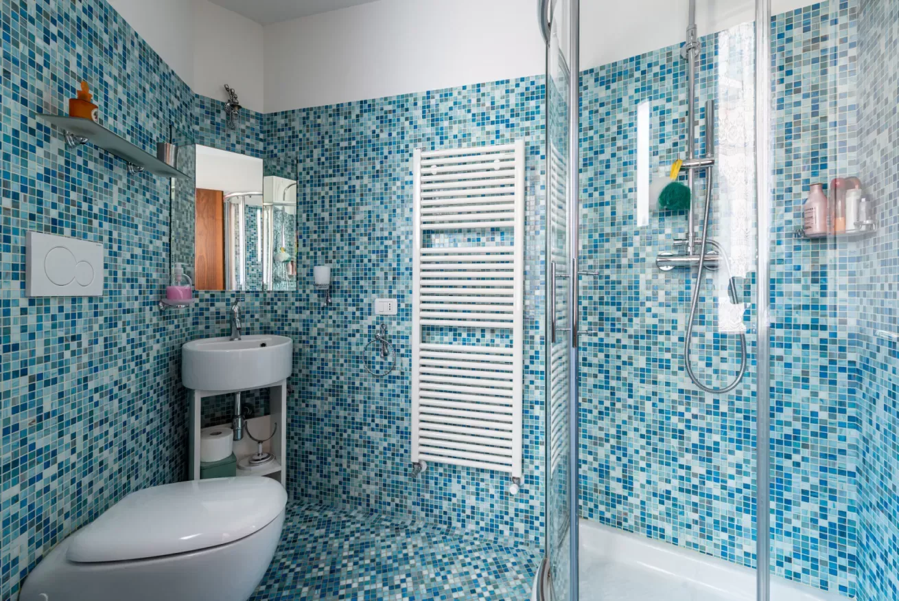 Baño con azulejos, lavabo, inodoro y ducha de vidrio.