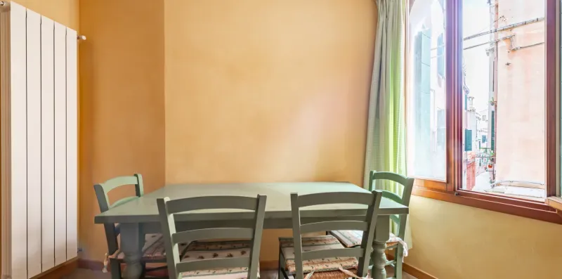 Comedor con una mesa y sillas junto a una ventana grande.