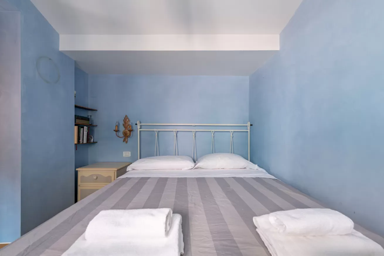 Un dormitorio con una cama de metal y toallas dobladas sobre la colcha a rayas.