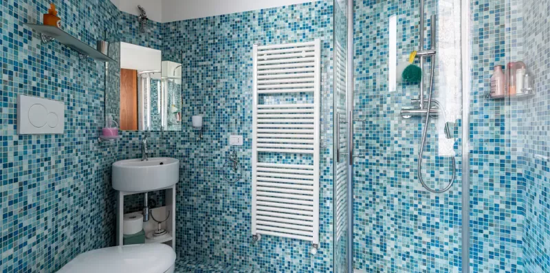 Un baño con azulejos, lavabo, inodoro y ducha de cristal.