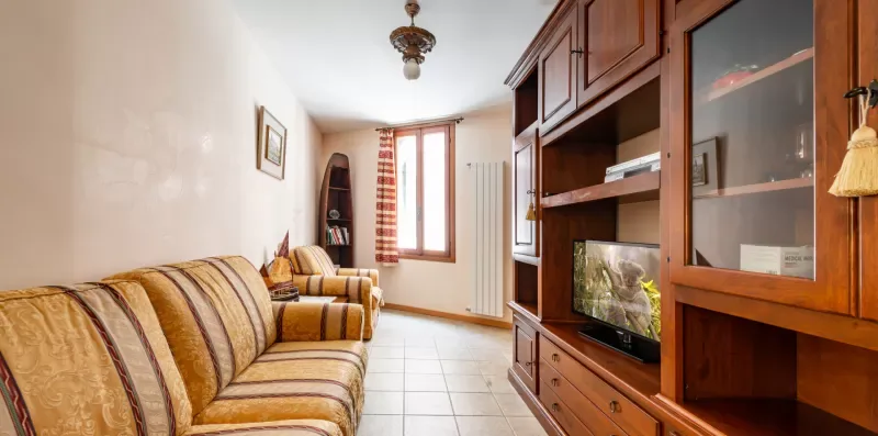 Una sala de estar con asientos a rayas, un televisor y una ventana.