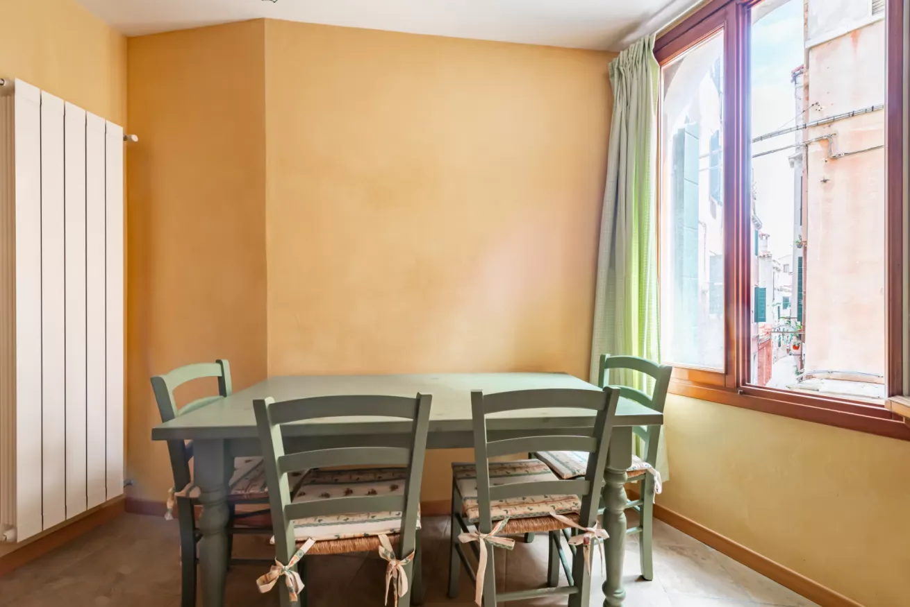Comedor con una mesa y sillas junto a una ventana grande.