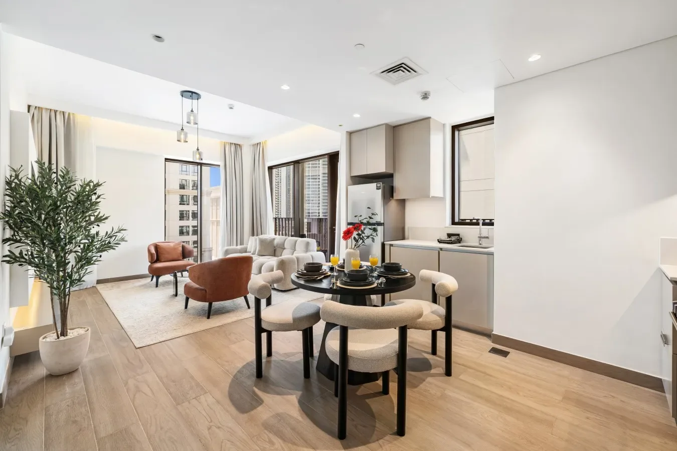 Sala de estar y comedor de planta abierta, con cocina y grandes ventanas.