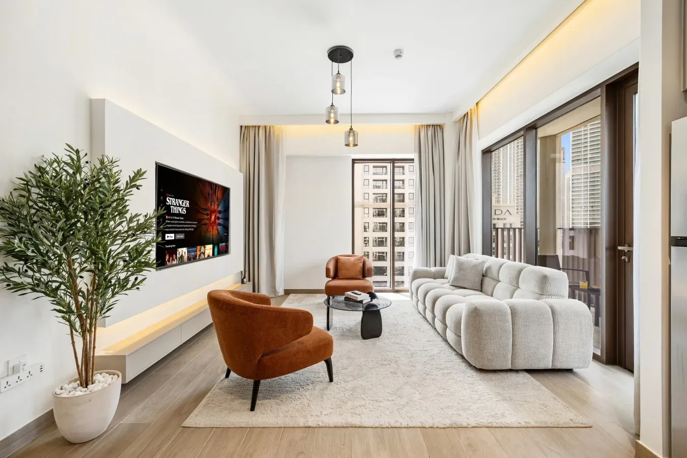 Una sala luminosa tiene asientos alrededor de una pequeña mesa de centro junto a grandes ventanas.