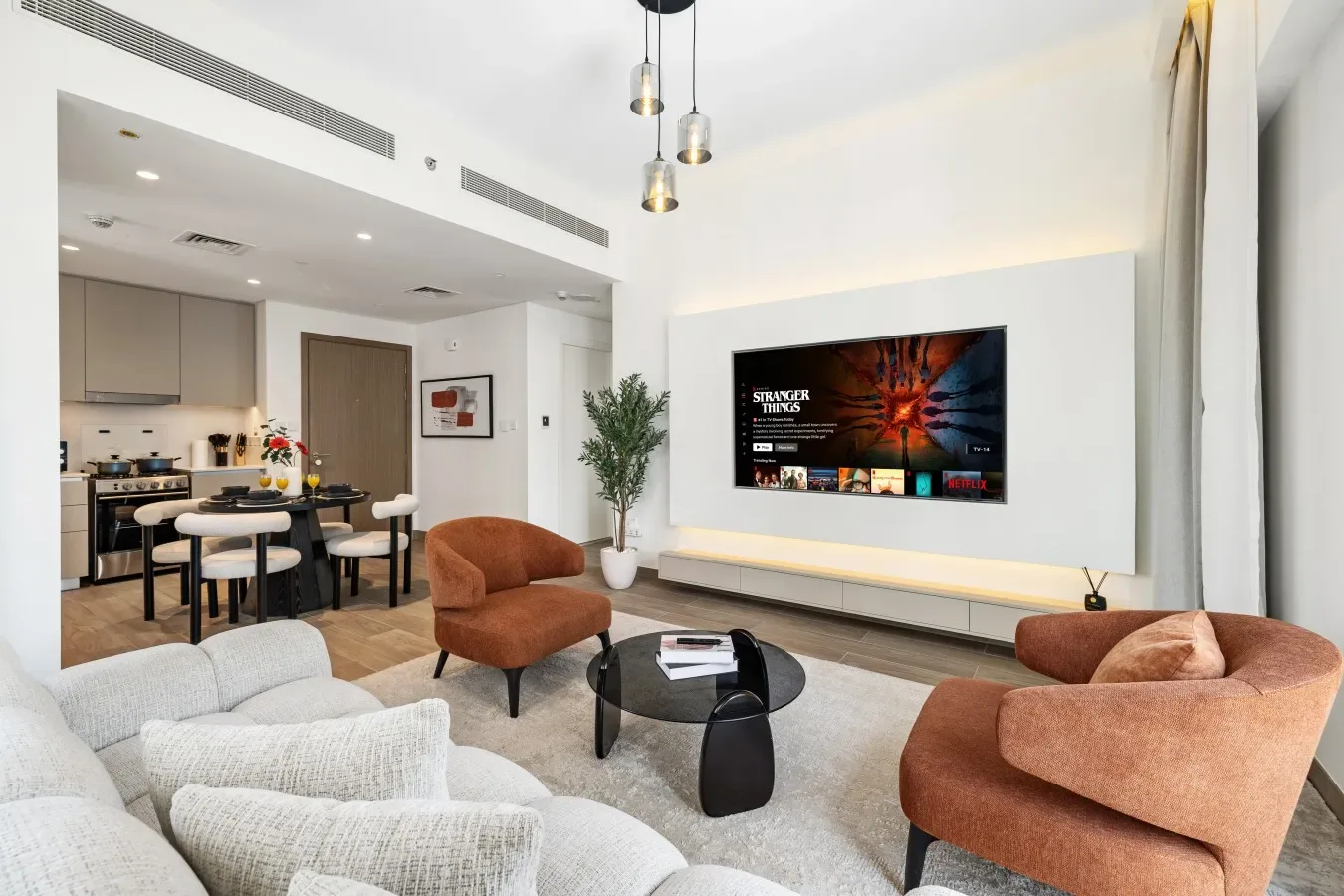 Una sala de estar de planta abierta con asientos, un televisor y una zona de cocina.
