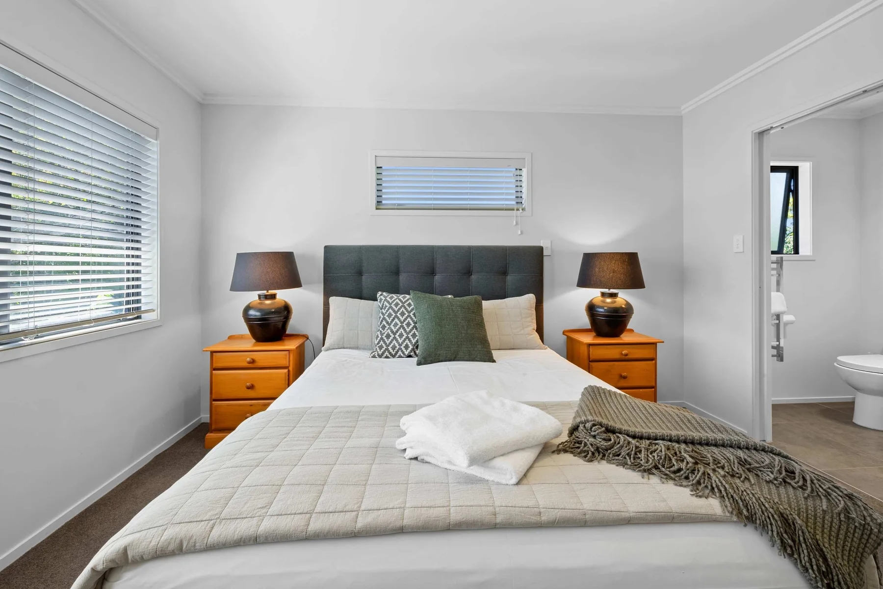 Un dormitorio luminoso con una cama arreglada y mesitas de noche.