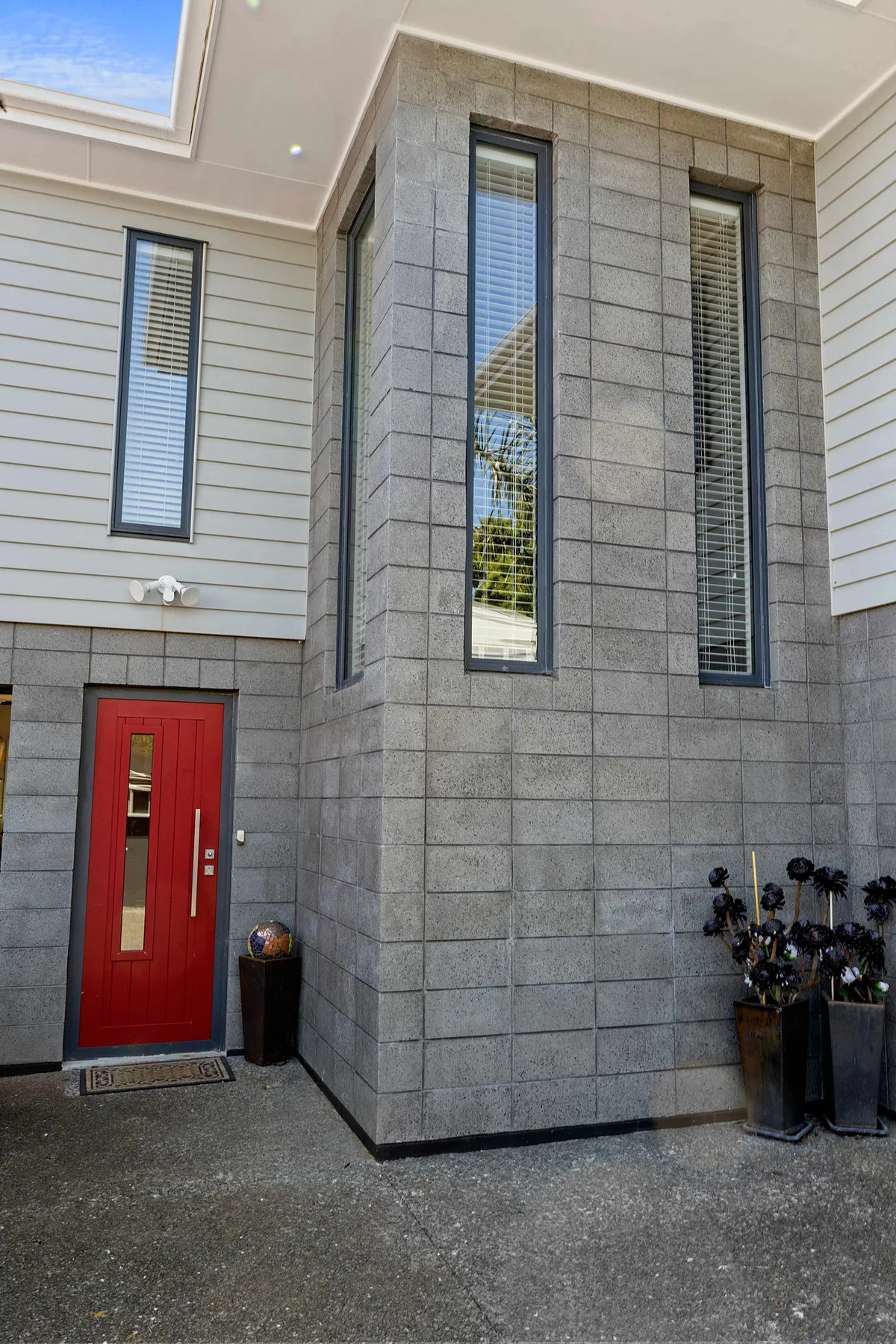 Entrada de un edificio moderno con una puerta roja y ventanas altas.