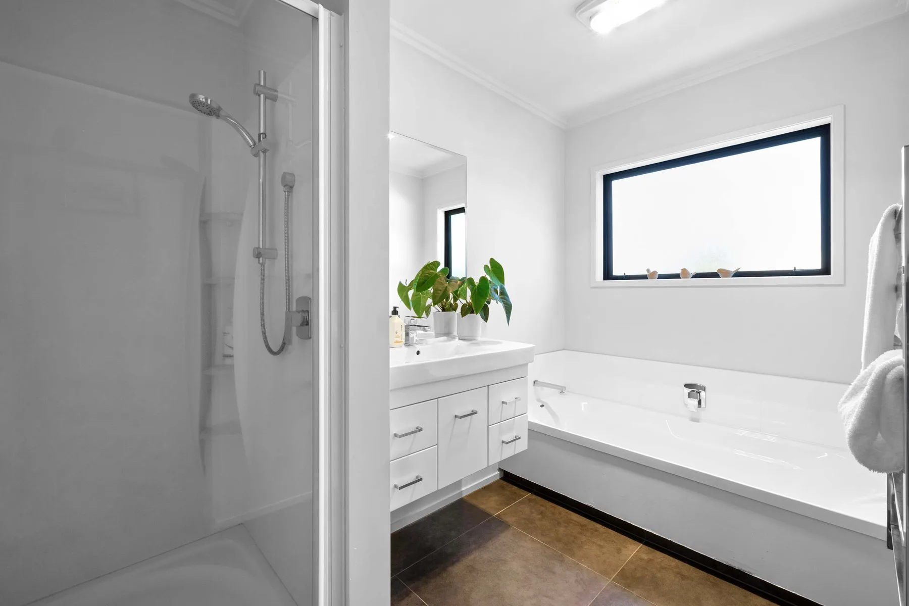 Un baño luminoso con ducha, bañera y lavabo.