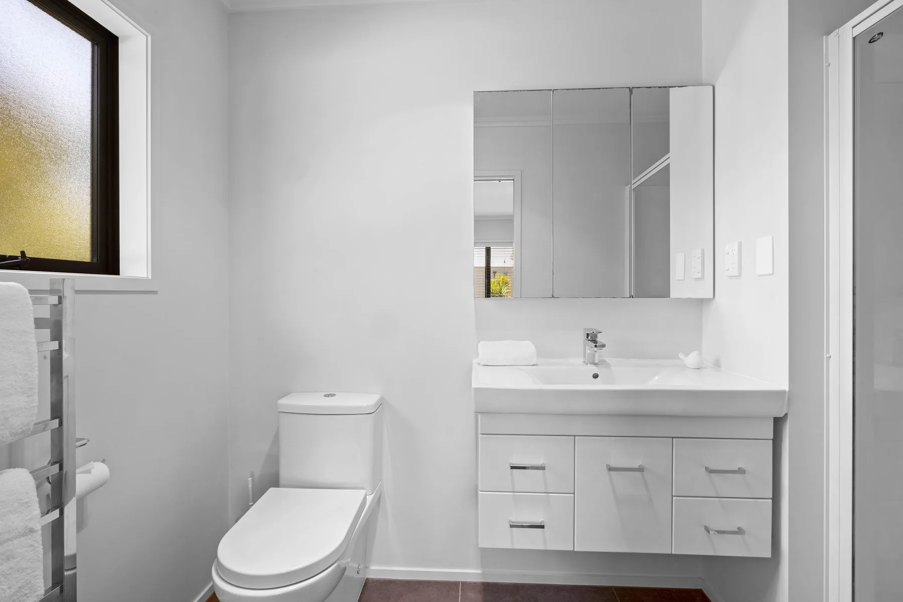 Un baño luminoso con inodoro, lavabo y armario con espejo.