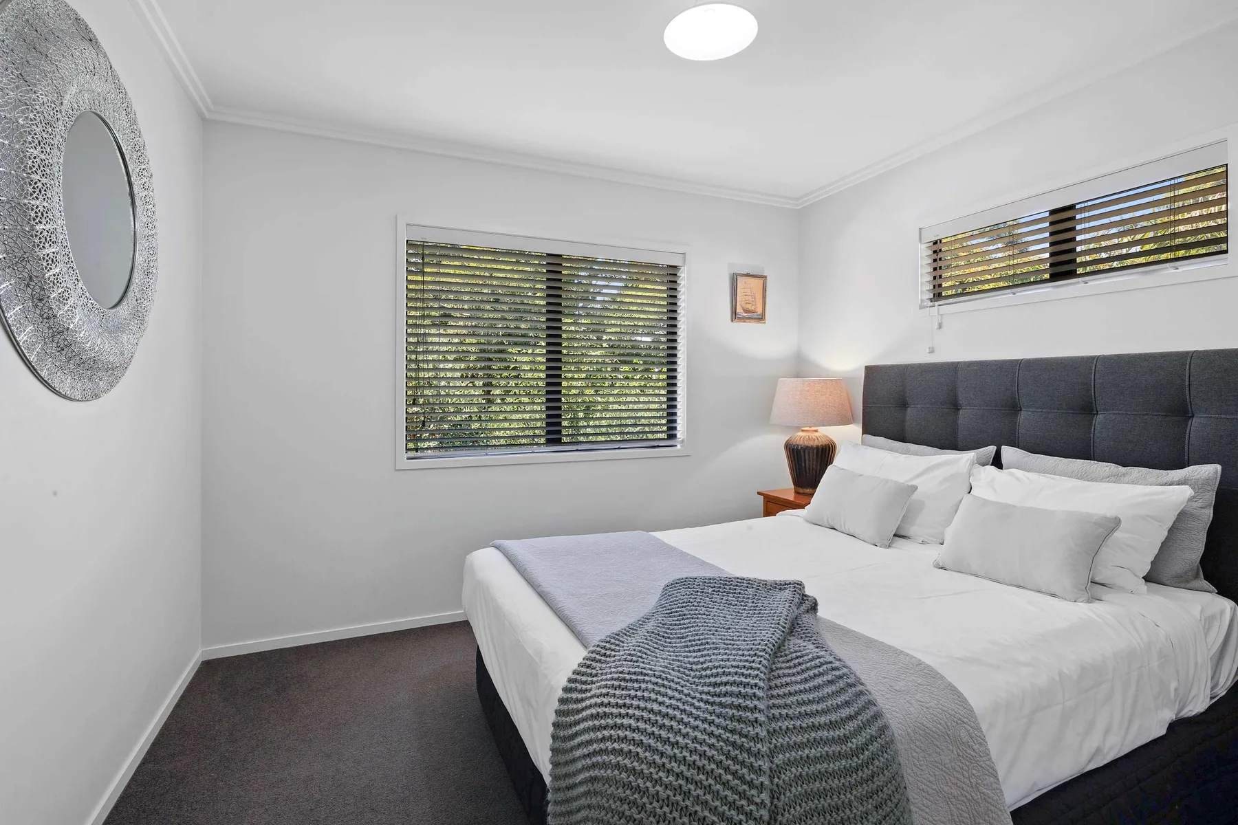 Un dormitorio luminoso con una cama grande y ventanas con persianas.