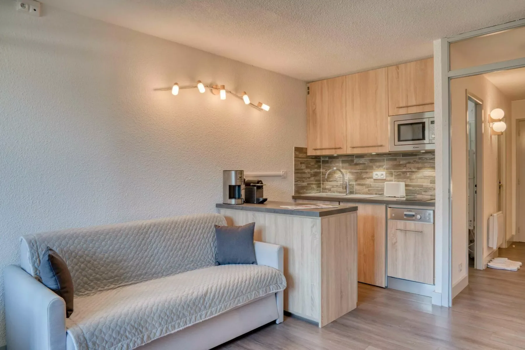 A living area with a sofa beside a compact kitchen.