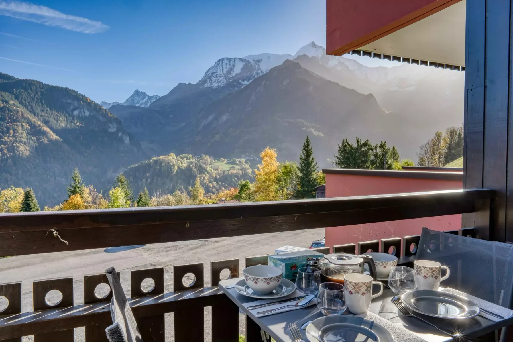 A balcony dining table overlooks a mountain valley.