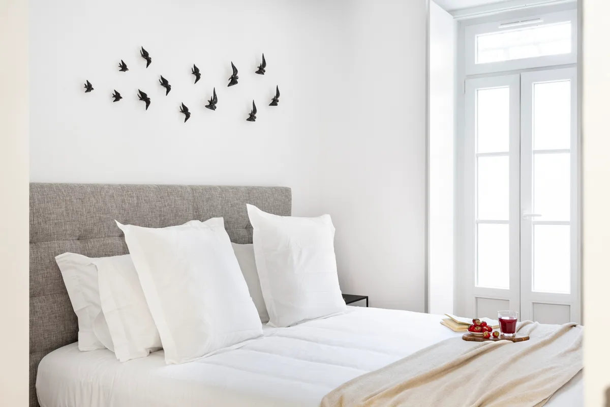 Un dormitorio con una cama bien arreglada y adornos de aves en la pared.