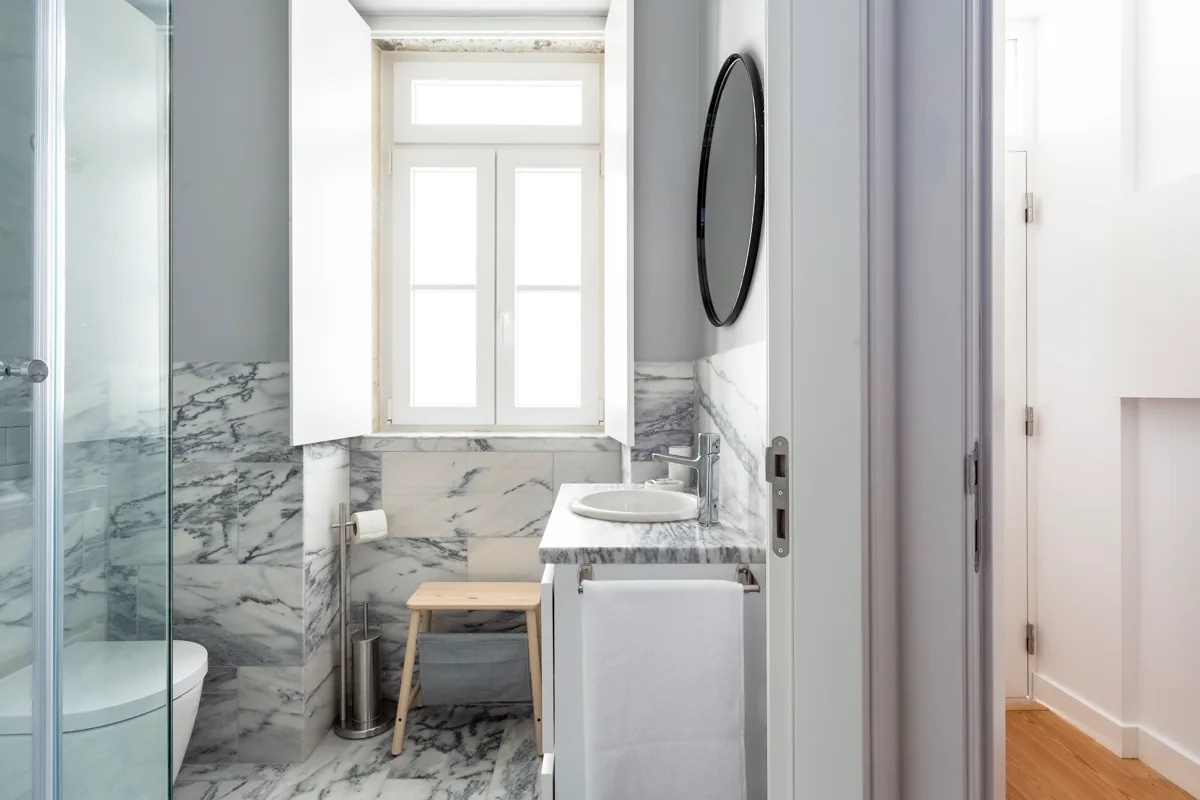 Un baño luminoso con lavabo, espejo y ducha de vidrio.