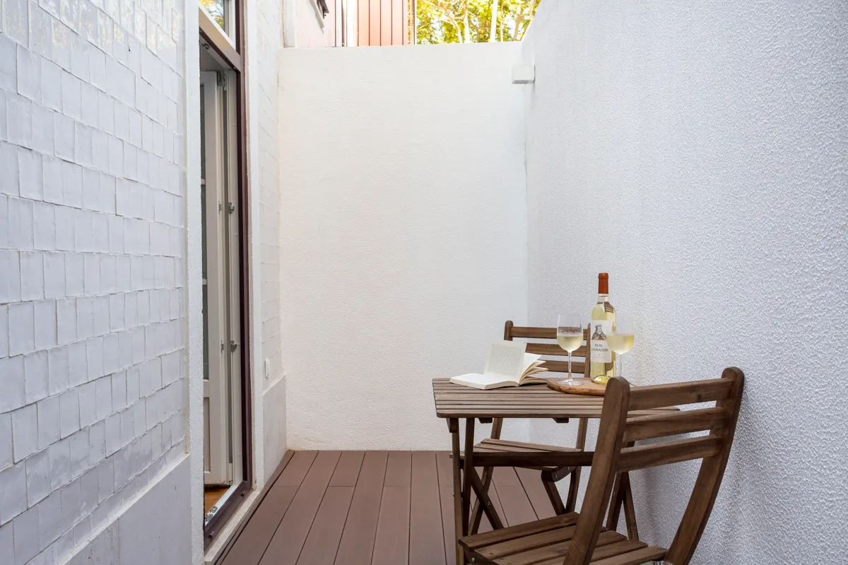 Una pequeña zona de comedor exterior con mesa y sillas de madera.
