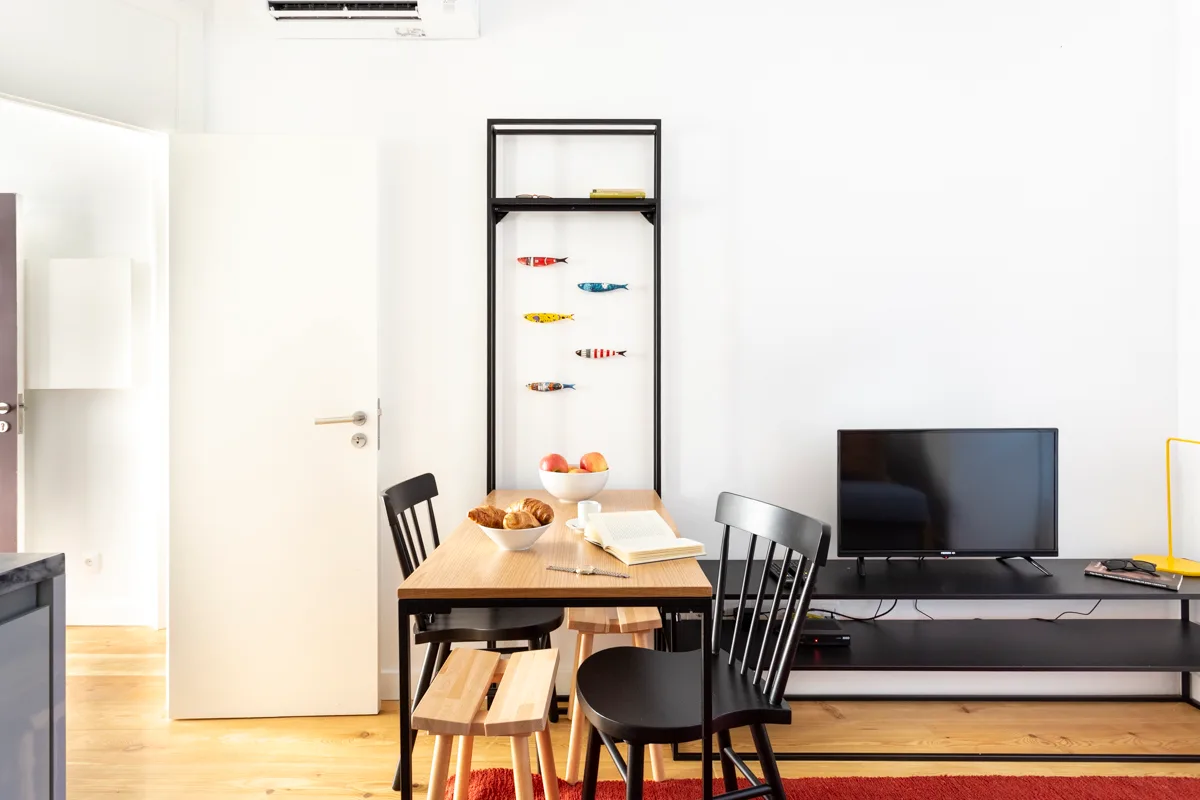 Zona de comedor y estar con una mesa, sillas y televisor.