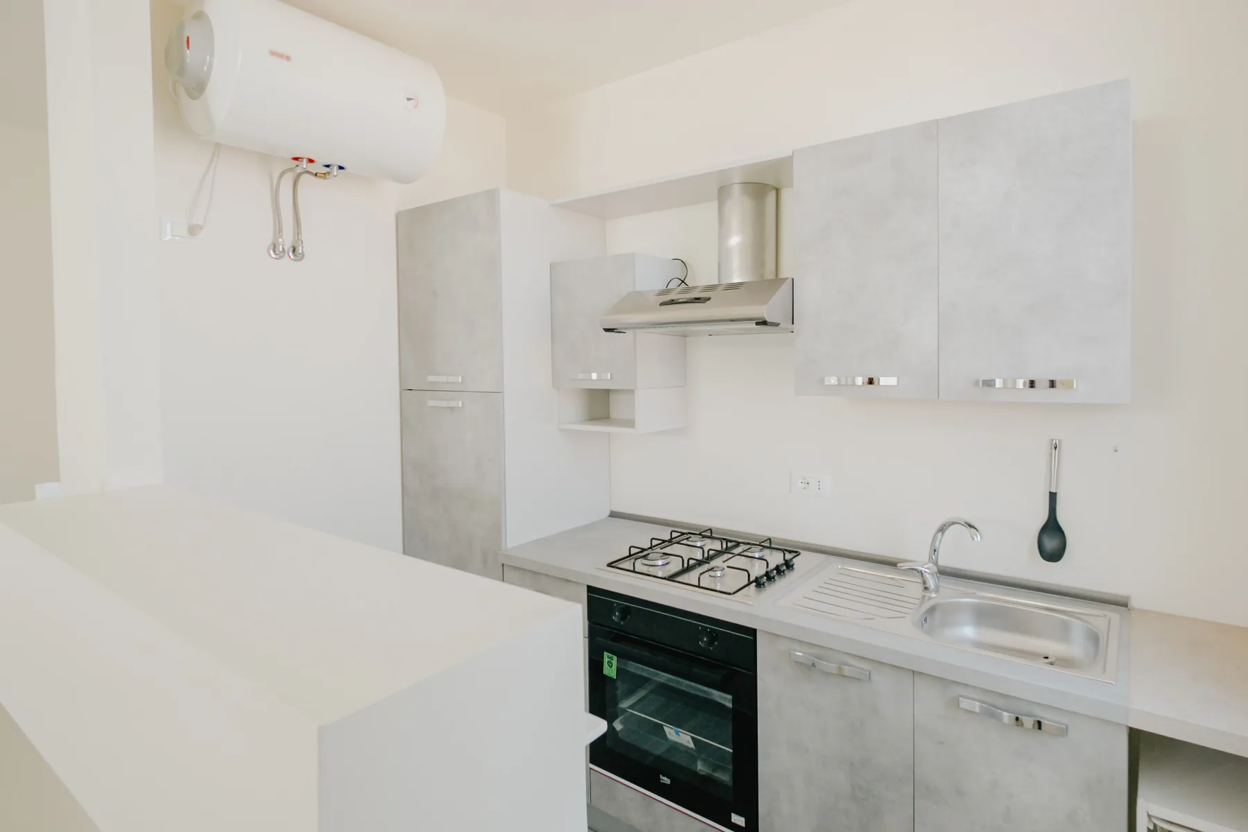 Una cocina luminosa con placa de cocina, horno, fregadero y armarios claros.