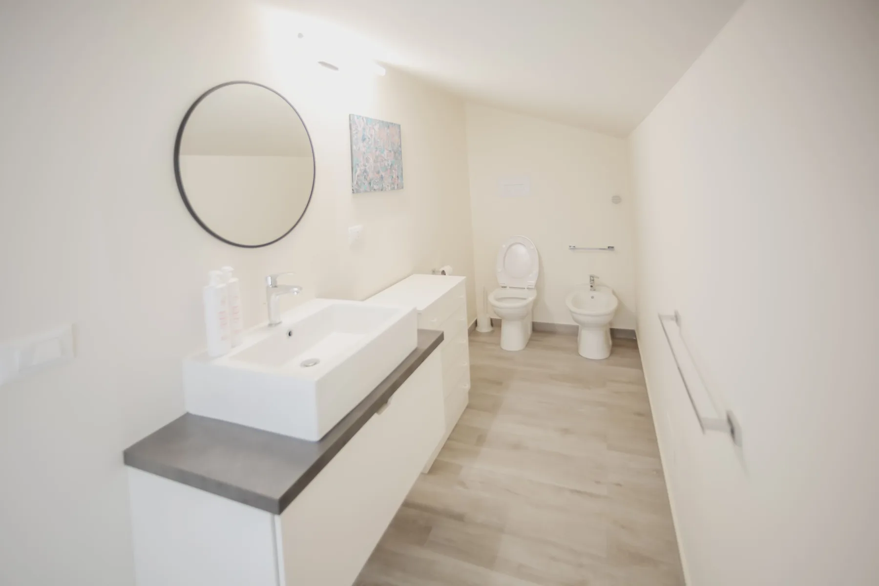 Un baño luminoso con un tocador de doble lavabo e inodoro.