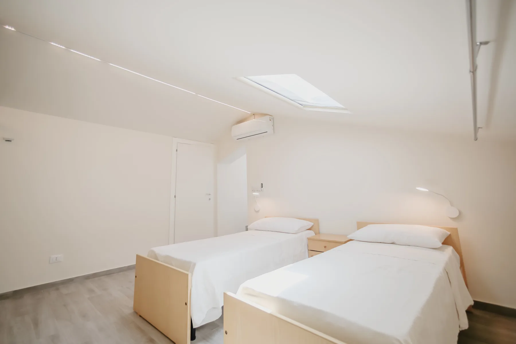 Un dormitorio luminoso con dos camas bajo una claraboya.