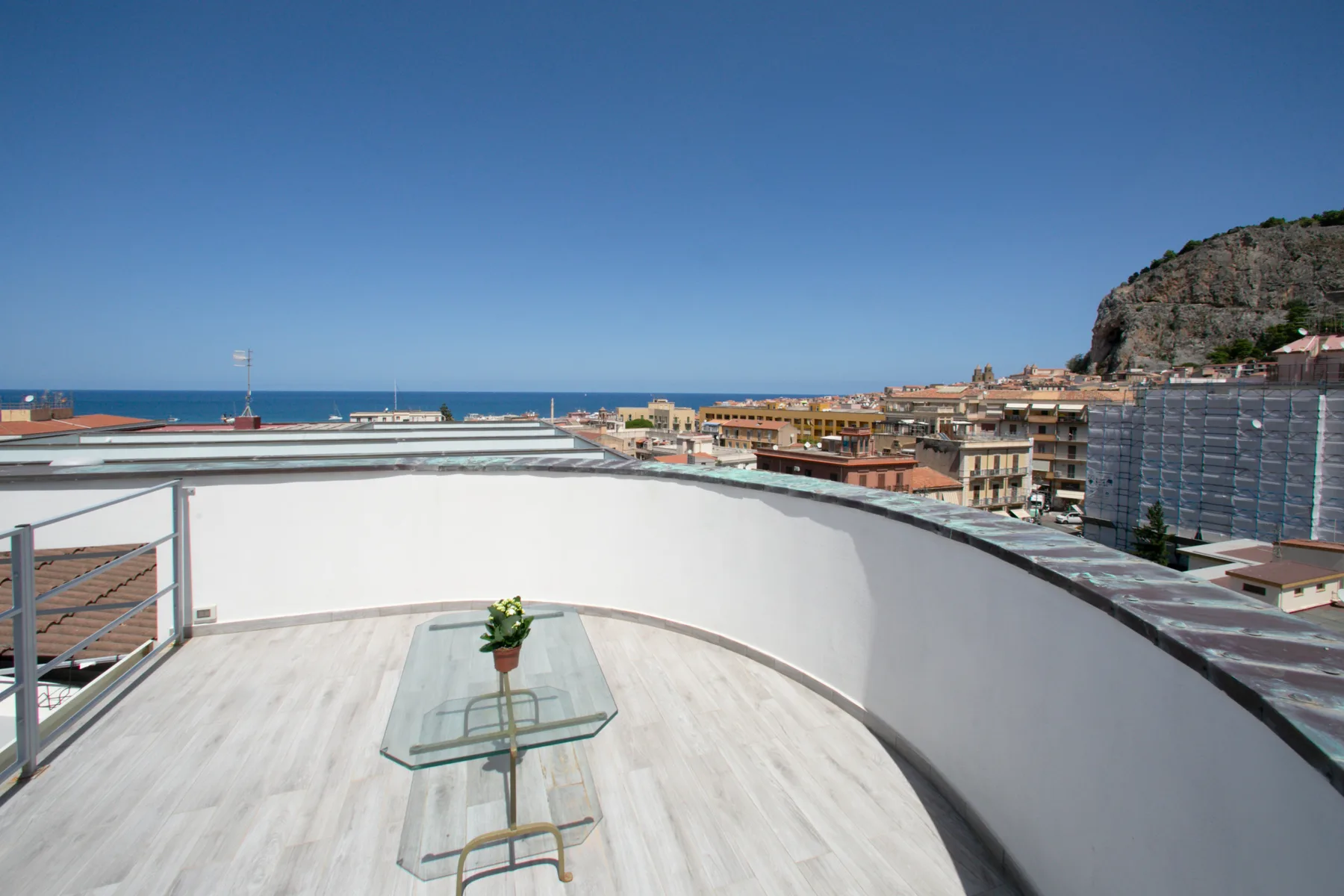 A curved rooftop terrace overlooks coastal buildings and the sea.