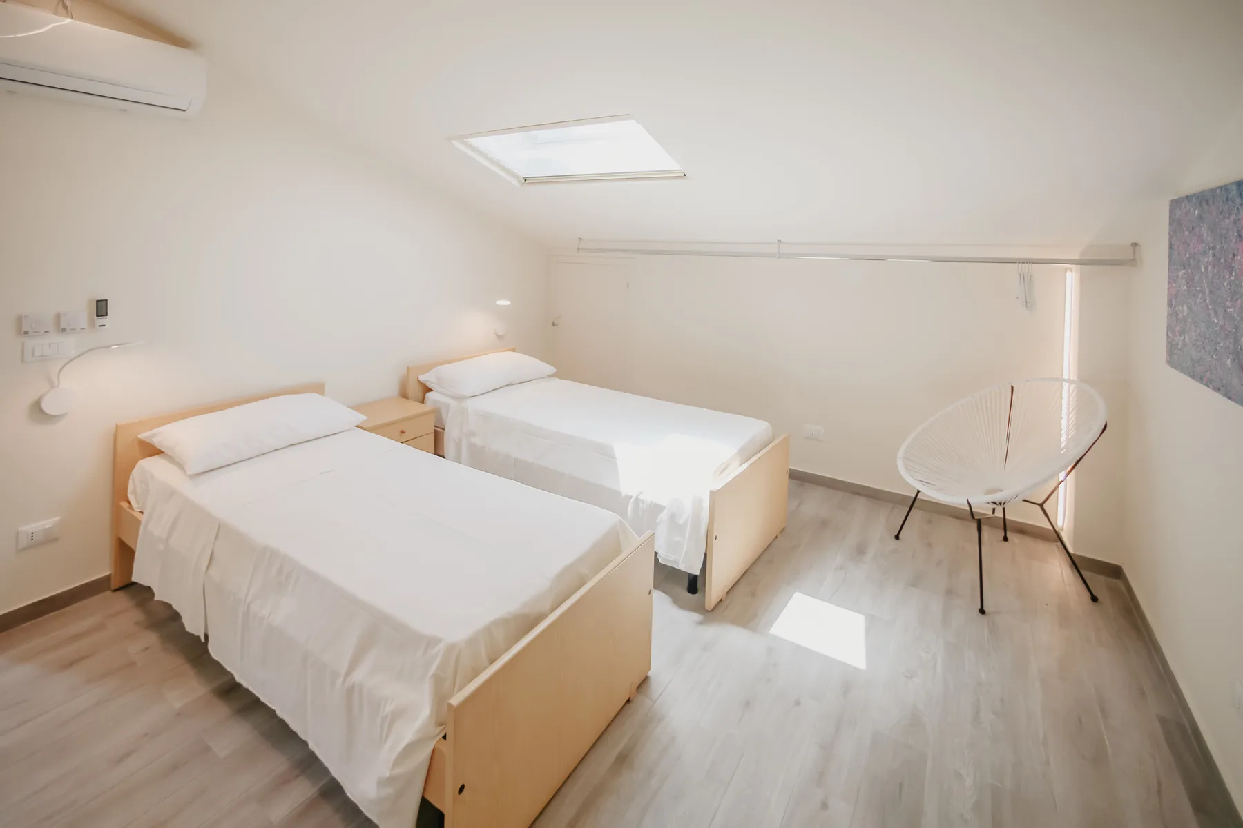 Un dormitorio luminoso con dos camas y una zona de estar curva.