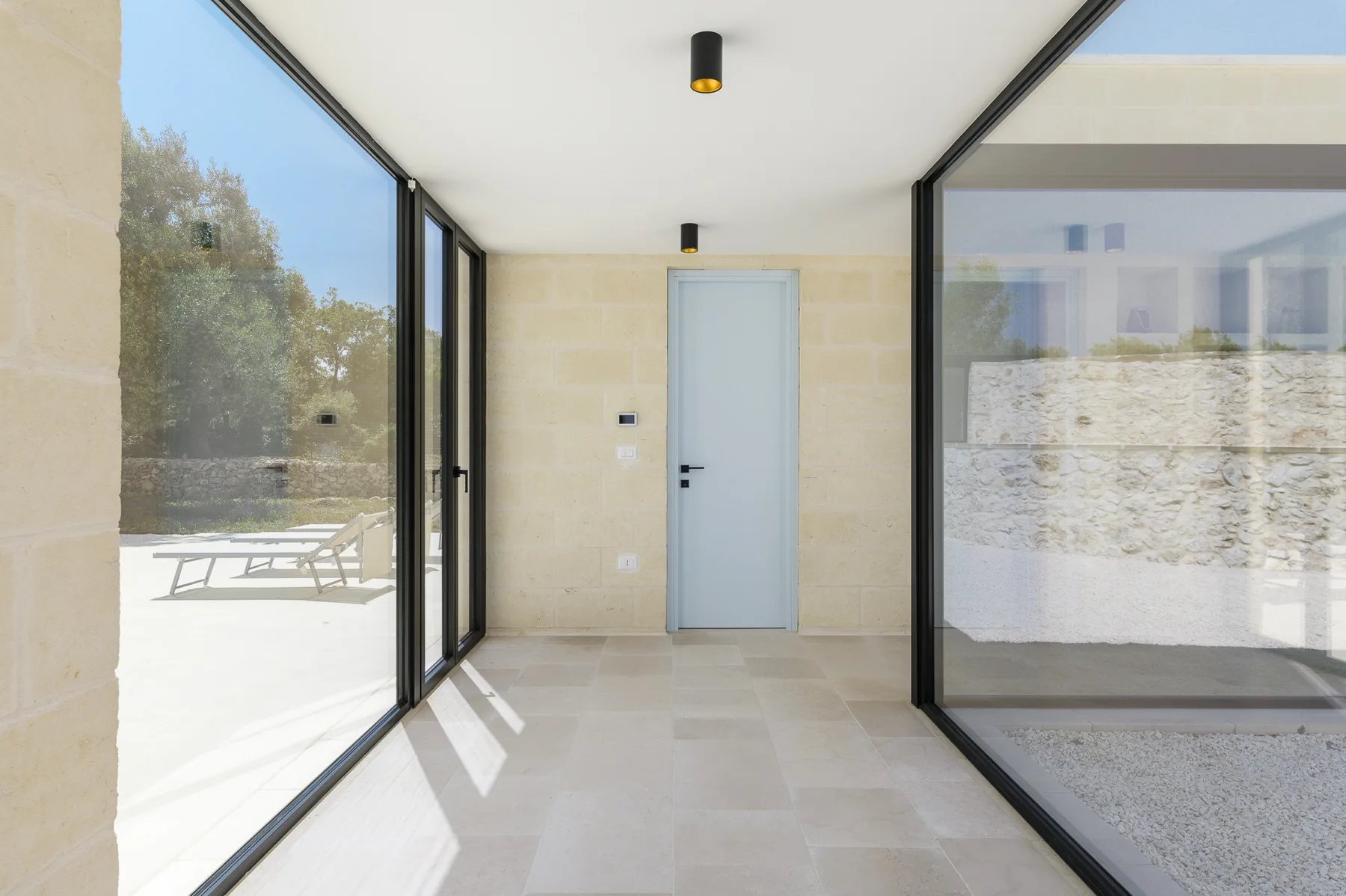 A bright entryway with a pale door and large glass walls.