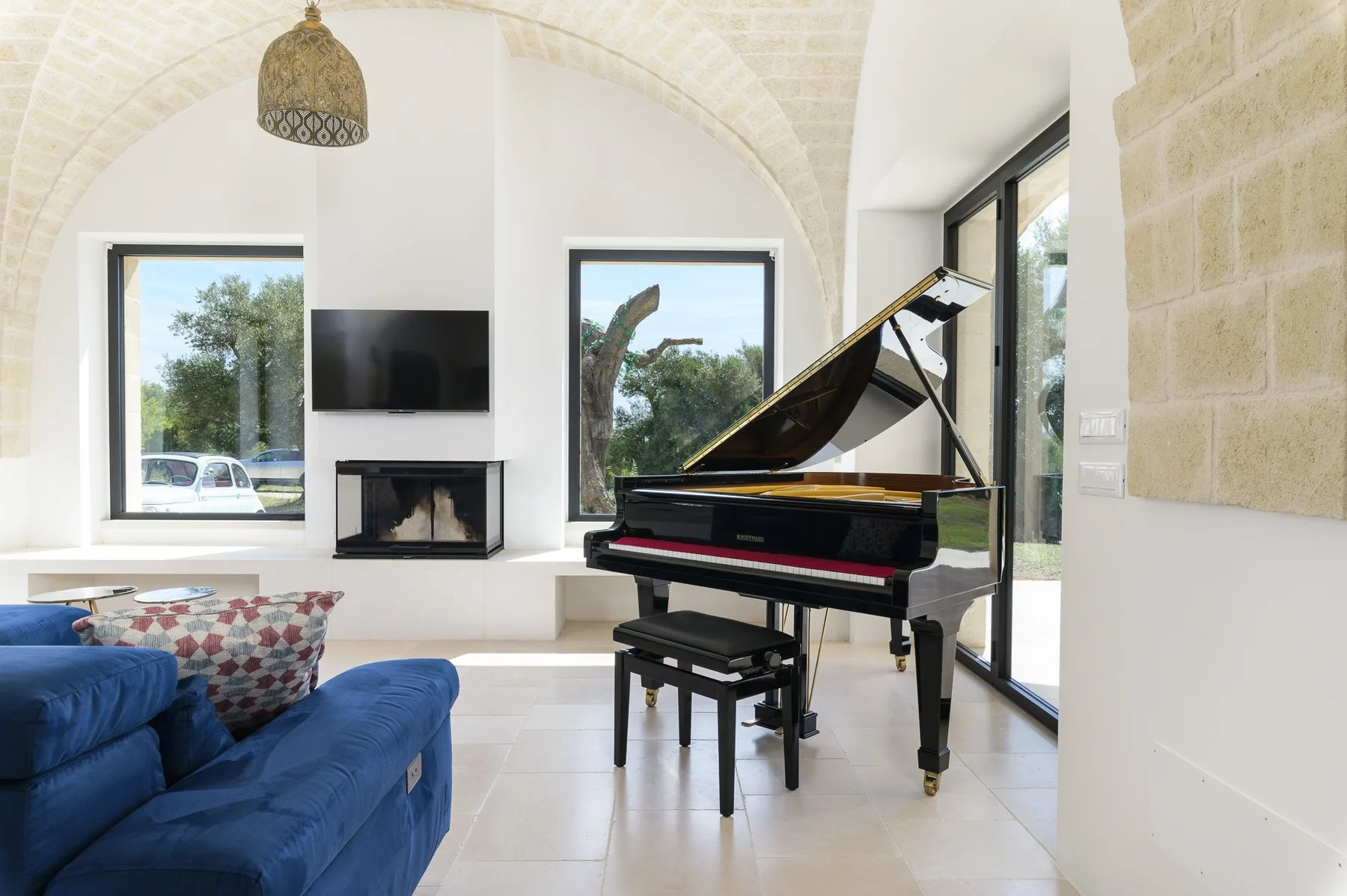 A bright living room with a grand piano and blue seating.
