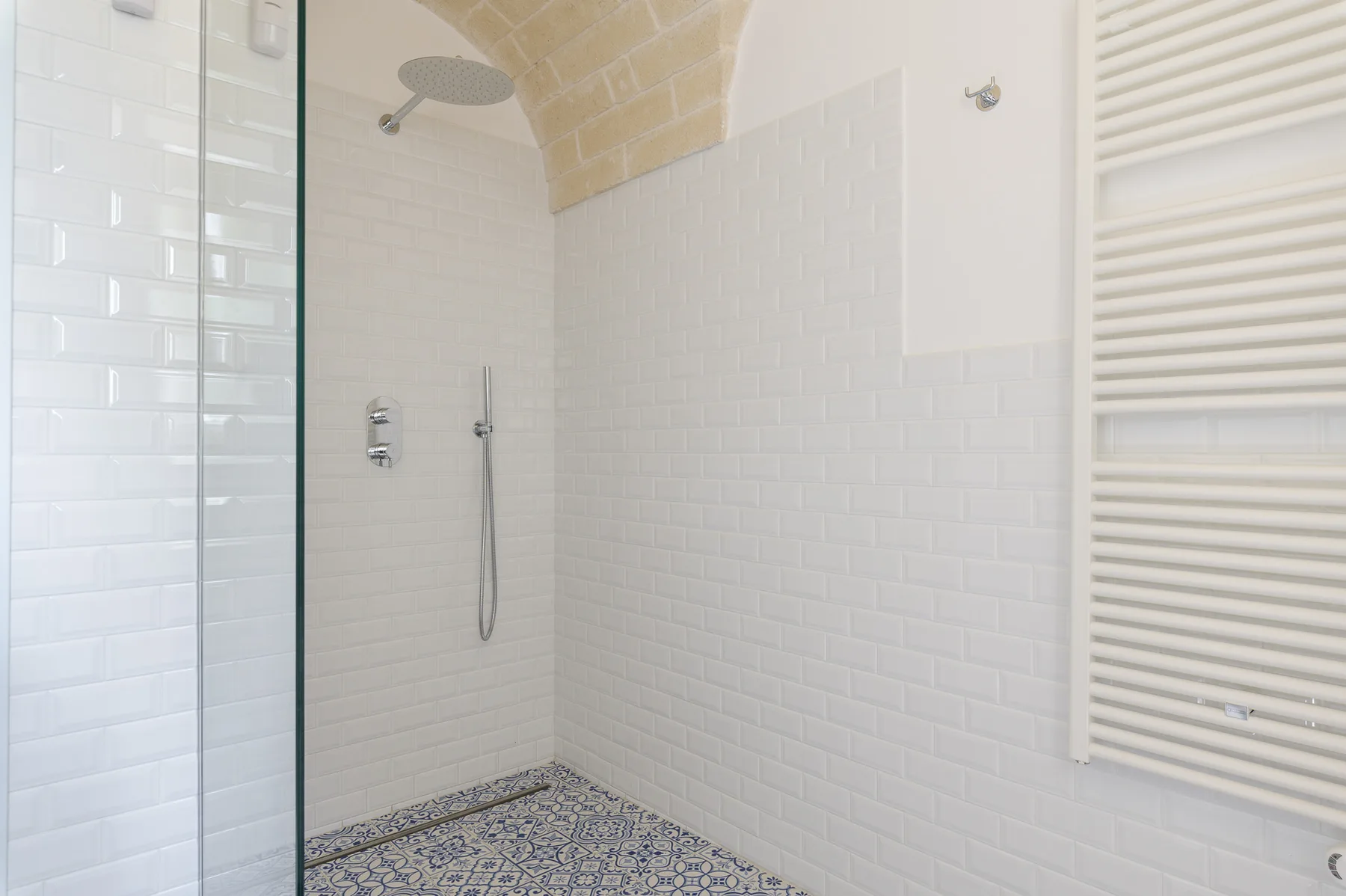 A tiled shower area with a patterned floor and a wall-mounted shower head.