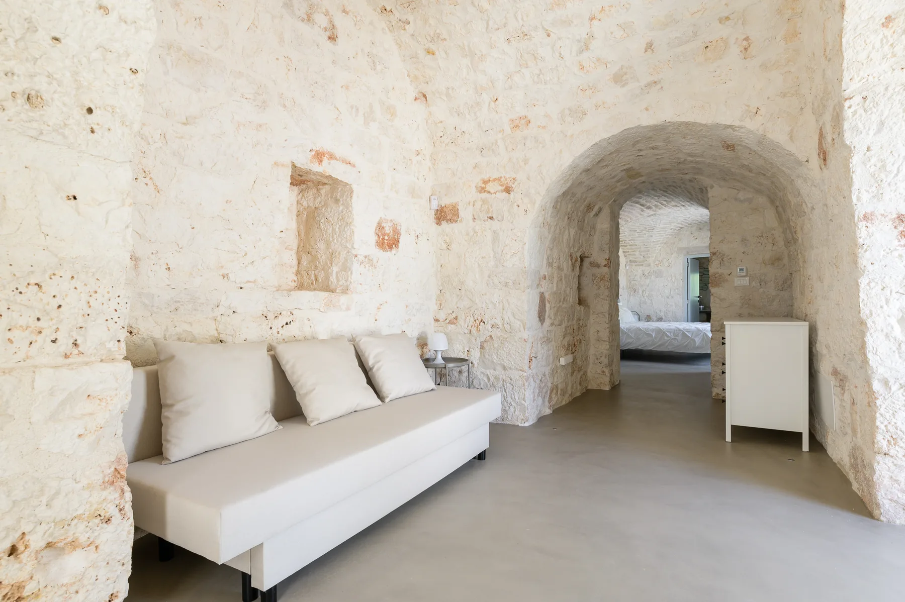 A stone-walled room with a built-in archway and a long upholstered seat.